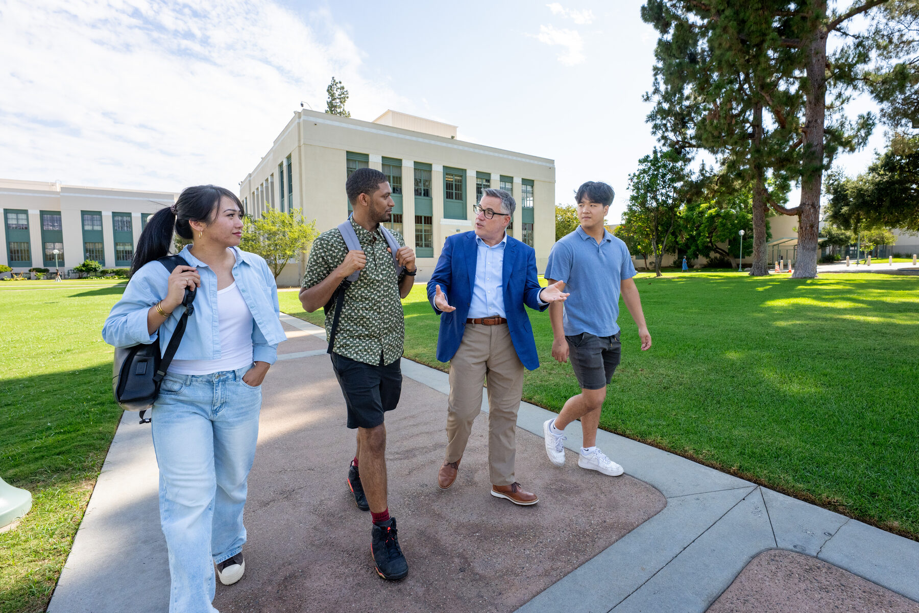 Geoff Baum talking with three students on the lawn of the Pasadena City College campus.