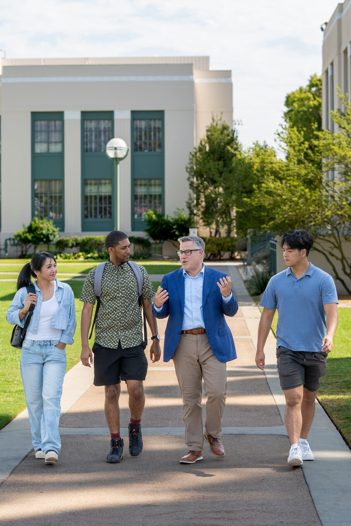 Geoff Baum walking across the Pasadena City College campus with students on a bright afternoon.
