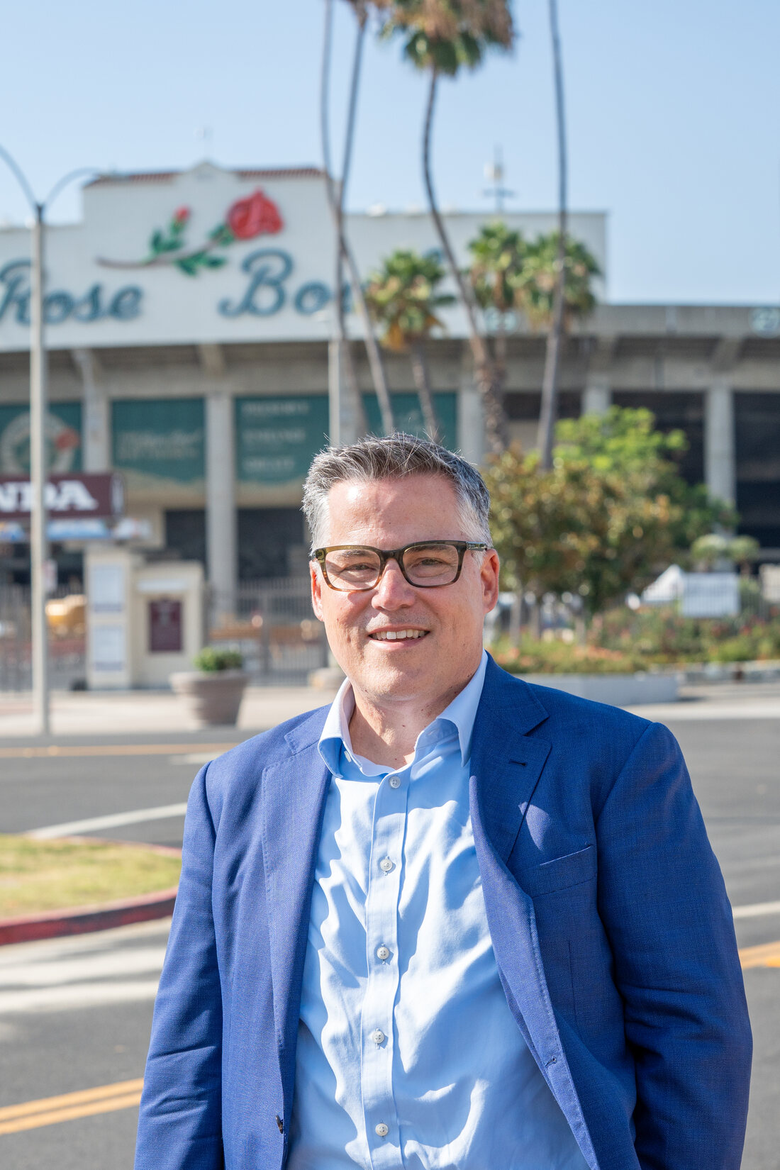 Portrait of Geoff Baum in a blue blazer standing outside the Rose Bowl in Pasadena.